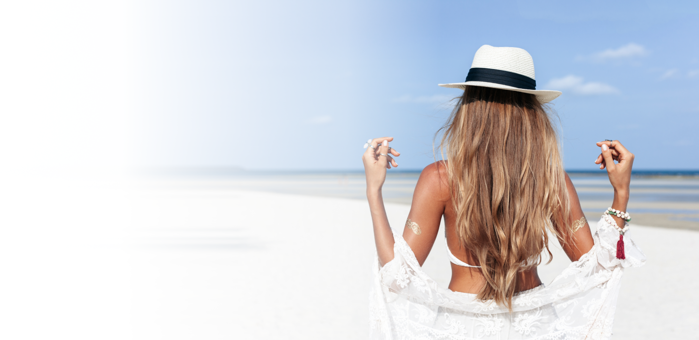 Back view of a woman with glowing skin and a sunhat, symbolizing confidence and wellness inspired by healthy skin practices.